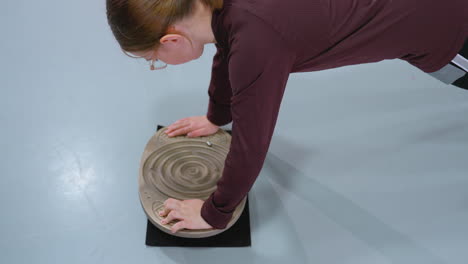 aerial view of young girl performing stability exercise on balance board to enhance core strength and balance, with reflection of another person visible on gym floor in background