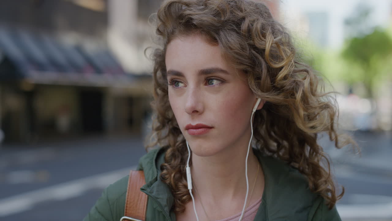 портрет красивой женщины, ожидающей на городской улице, грустной, несчастной, носящей наушники, слушающей музыку, молодой кавказской женщины, размышляющей в городском фоне