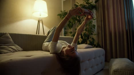 소파에 위아래로 누워 있는 여자, 플레어와 함께 사진 카메라를 사용하여, 가까이 가십시오