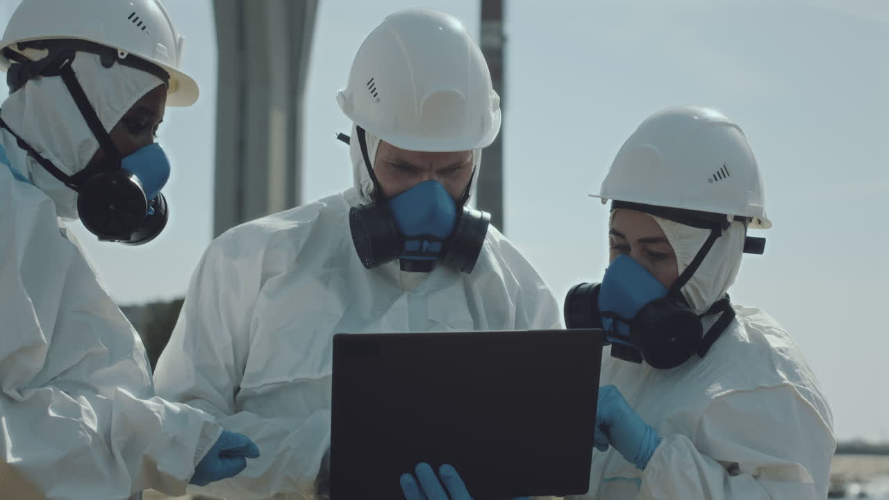 Team of Ecologists in Protective Wear Working with Laptop