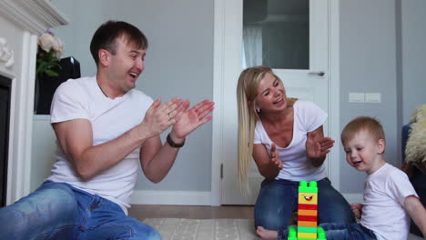 dad and mom clap their hands and rejoice at the success of the little son, whipping him for a wave of task from lego.