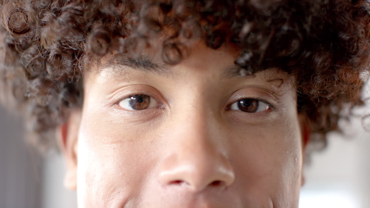 Close-up of young person with curly hair looking directly at camera