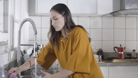 hermosa latina lavando platos en la cocina blanca