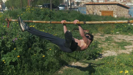Athletic-young-male-trains-static-straddle-front-lever-gymnastic-exercise-outdoors-shirtless