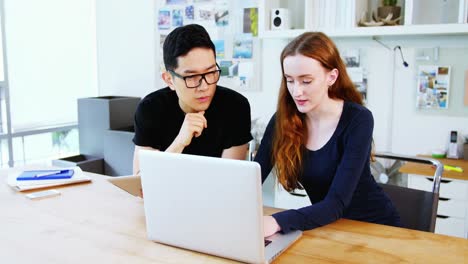 Business-executives-discussing-over-laptop