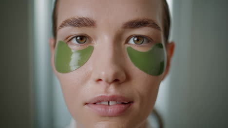 girl using eyes patches on home treatment closeup. serene model with collagen