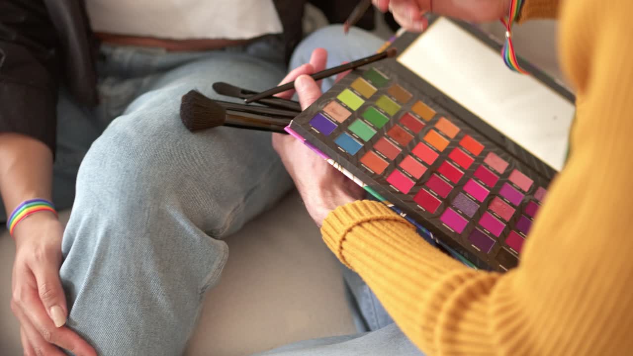 Close-up of hands holding a colorful makeup palette and brushes