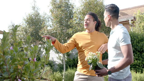 Happy-diverse-gay-male-couple-talking-in-sunny-garden,-copy-space,-slow-motion,-copy-space