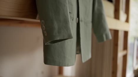 close up of green suit sleeve with buttons in soft home light