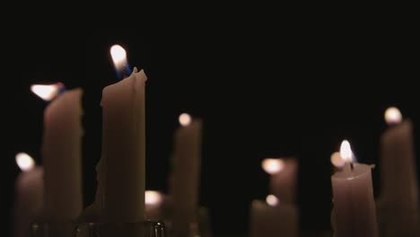 un primerísimo plano de velas blancas encendidas con un fondo negro