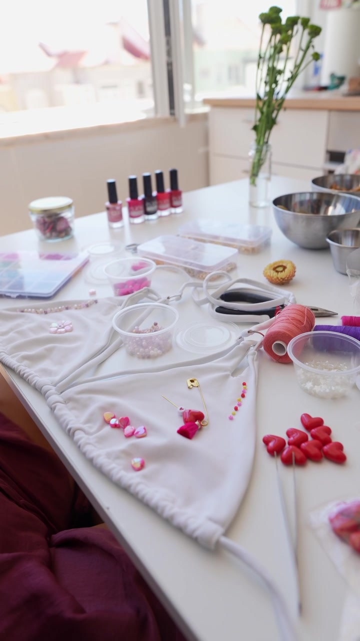 Persona che decora un top bikini bianco con perline e ciondoli