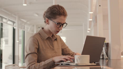 mujer joven trabajando en una computadora portátil en un café