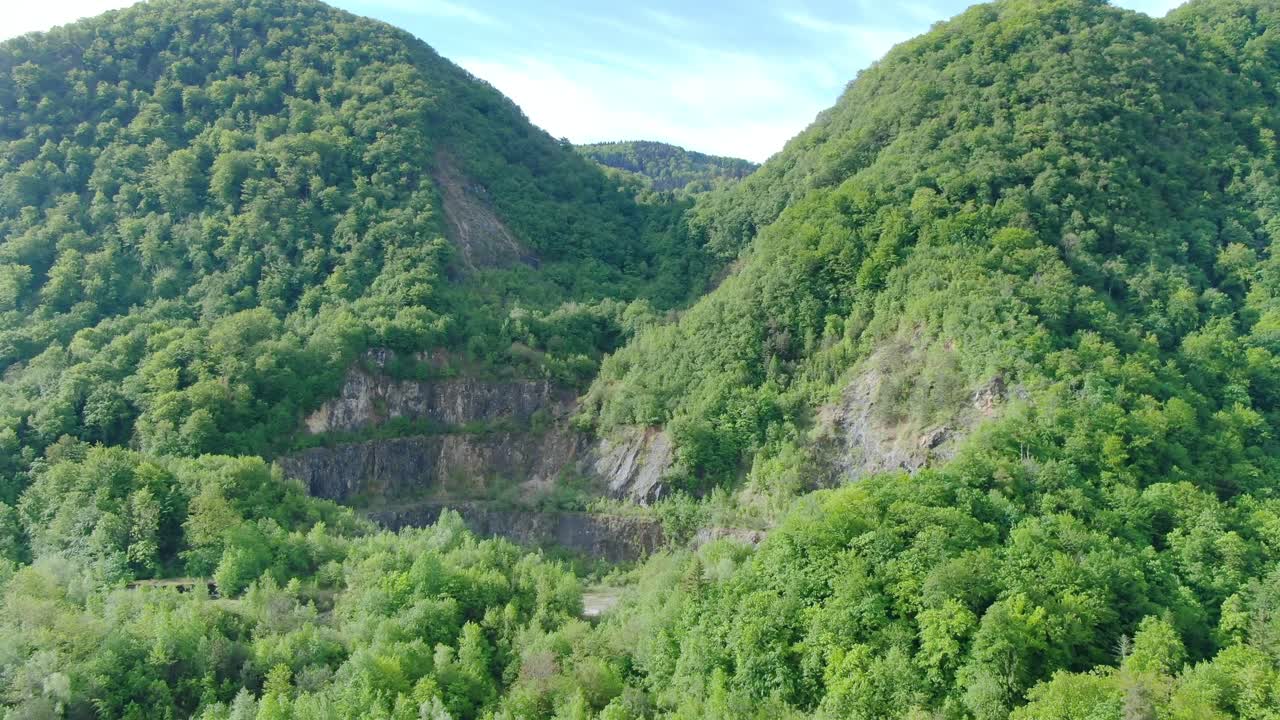 Fly over forest at the foot of mountains also completely covered with trees. Drone flight