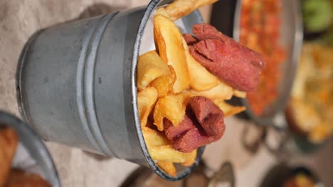 french fries and cut hot dogs served in a metal bucket