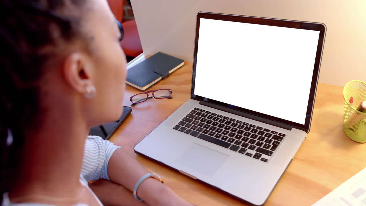 Black businesswoman views laptop at desk, slow motion.