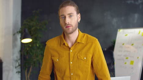 Young-Handsome-Man-In-Yellow-Shirt-With-Crossed-Hands-Smiling-To-Camera-In-The-Office-1