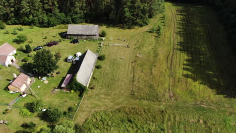 Group-of-people-play-volleyball-in-rural-recreational-homestead,-aerial-fly-back-reveal-shot