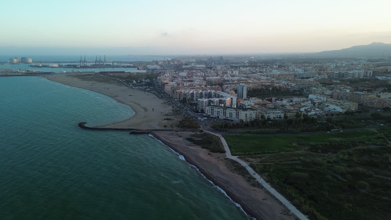 vista aérea de los edificios de una ciudad frente a la playa con un pájaro pasando delante de la cámara