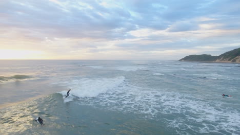 cinematic aerial at sunrise of surfers along coast of south africa sport