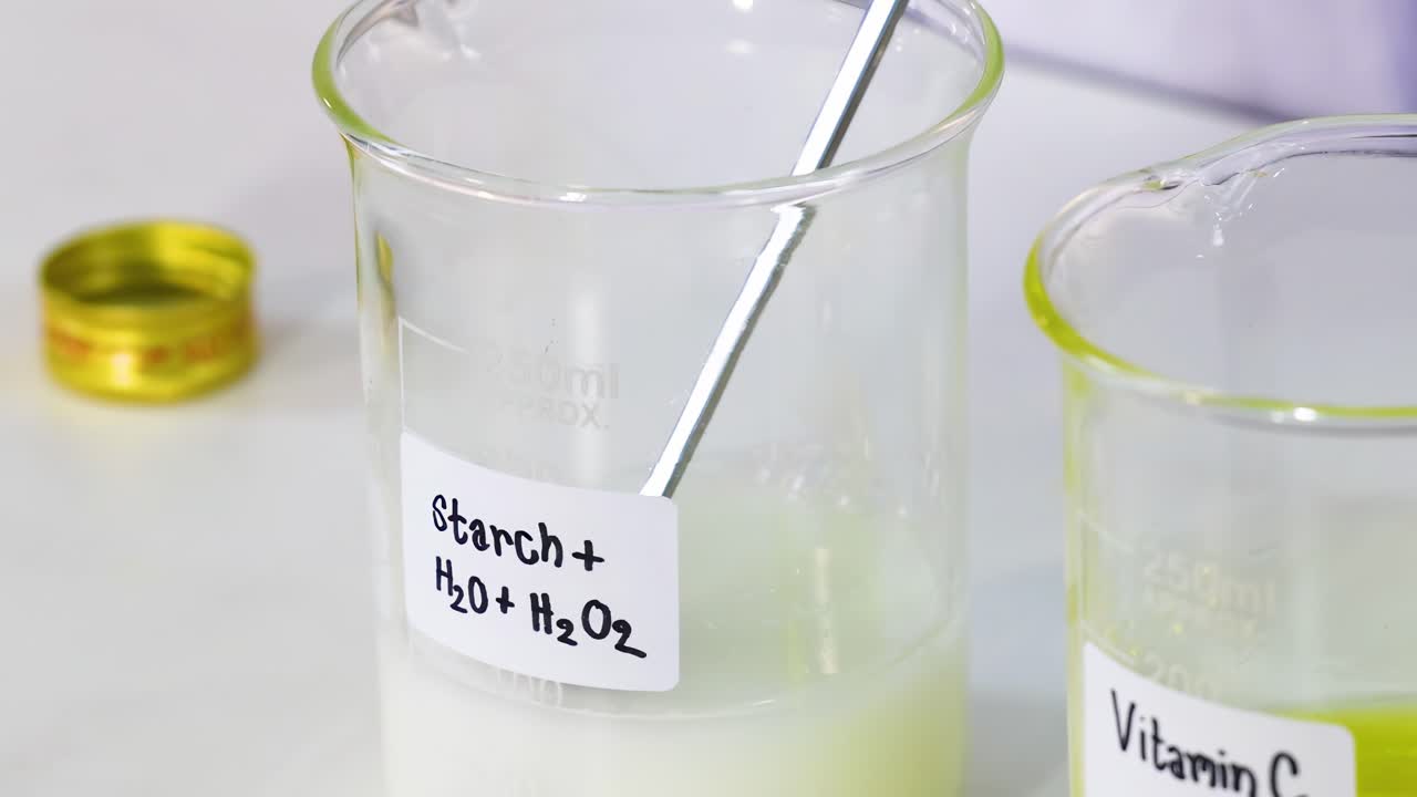 Close-up of a chemical reaction involving starch and hydrogen peroxide in labeled beakers.
