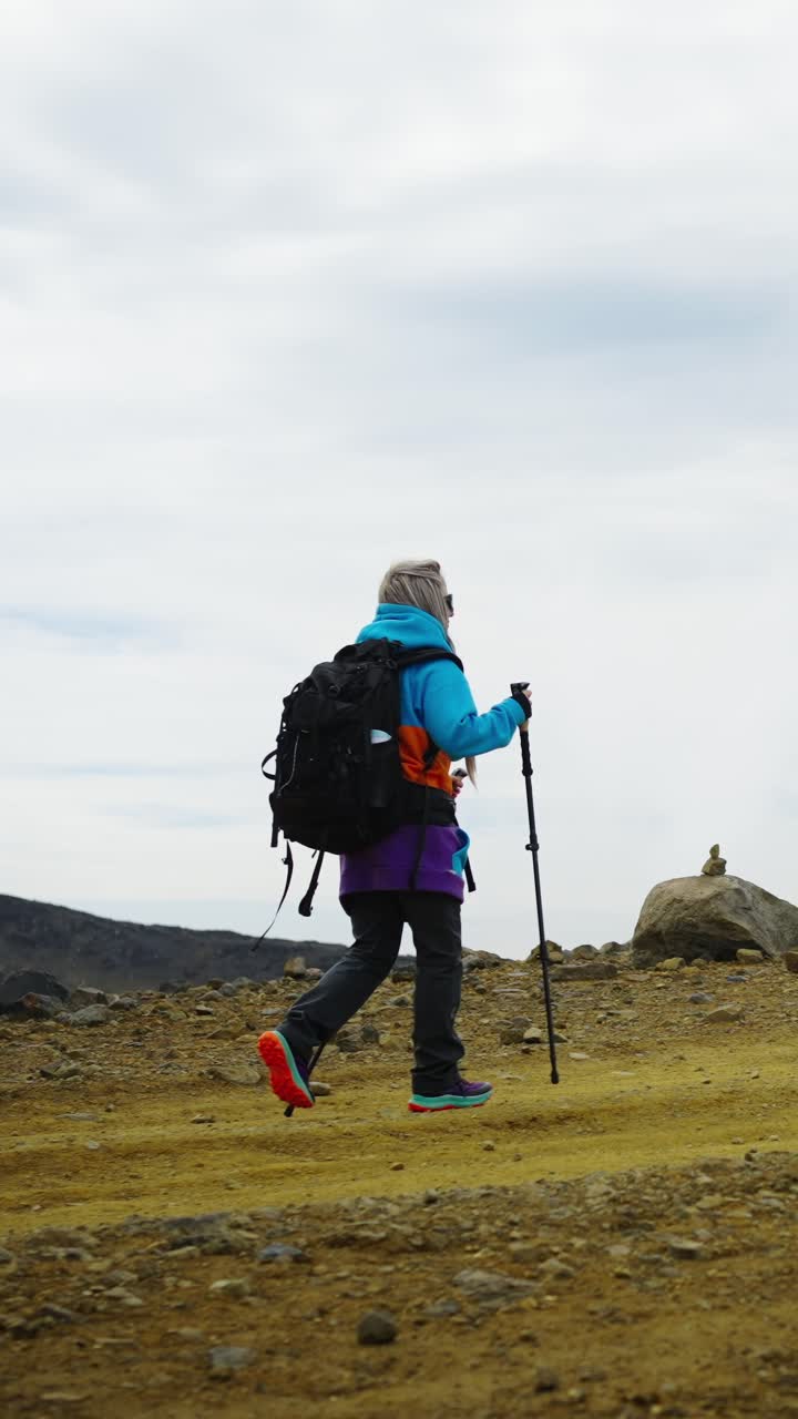 Donna in escursione su un sentiero di montagna roccioso con zaino.