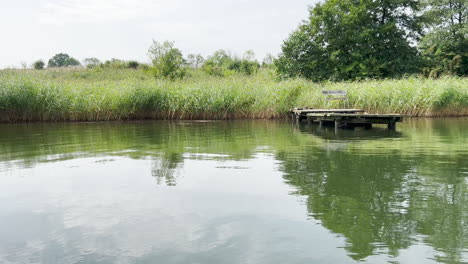 Ruhiges-Seewasser-Mit-Spiegelreflexion-Von-Grünem-Gras