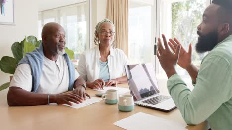 african american financial advisor and senior couple talking at home, slow motion