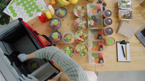 female worker in gloves packing eco food in delivery bag