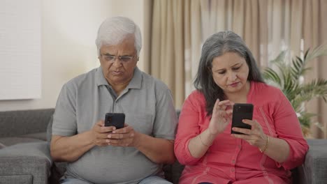old indian couple busy in their phones