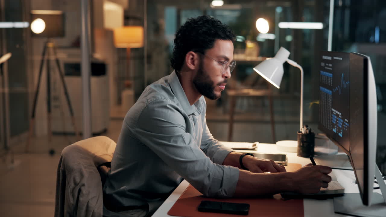 Man Working Late in Modern Office Analyzing Data on Computer