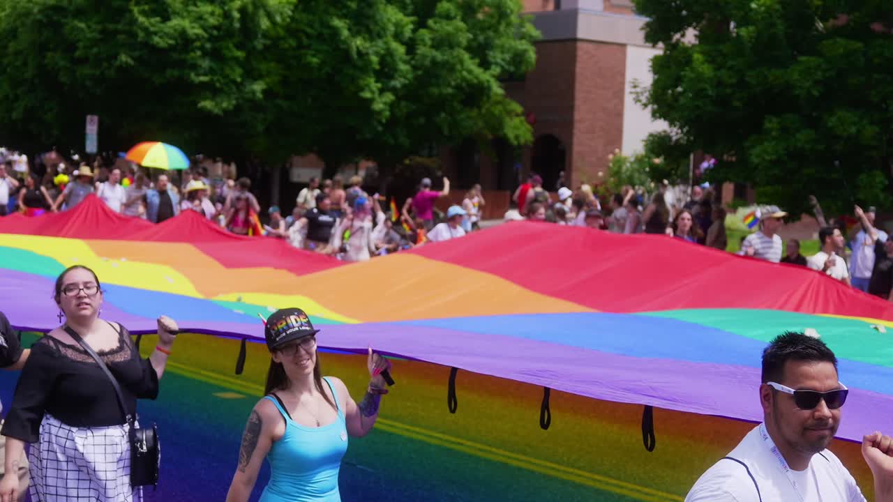 Clip of a HUGE rainbow flag being carried by multiple multi race diverse people at the 2024 Gay and Lesbian Pride Parade festival event on Sunday the 2nd of June in Salt Lake City Utah.