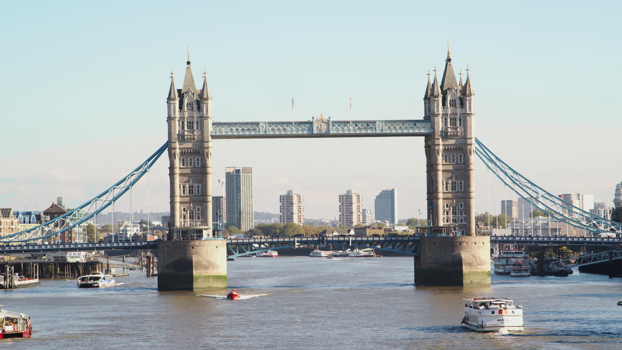 Sightseeingbåde, der sejler under Tower Bridge på Themsen på en solskinsdag i London.
