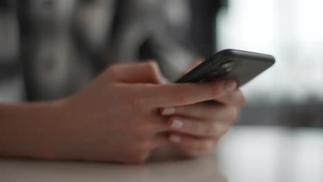 close-up cropped shot of unrecognizable young woman texting message on mobile phone for communication and chatting on social online sitting at desk.