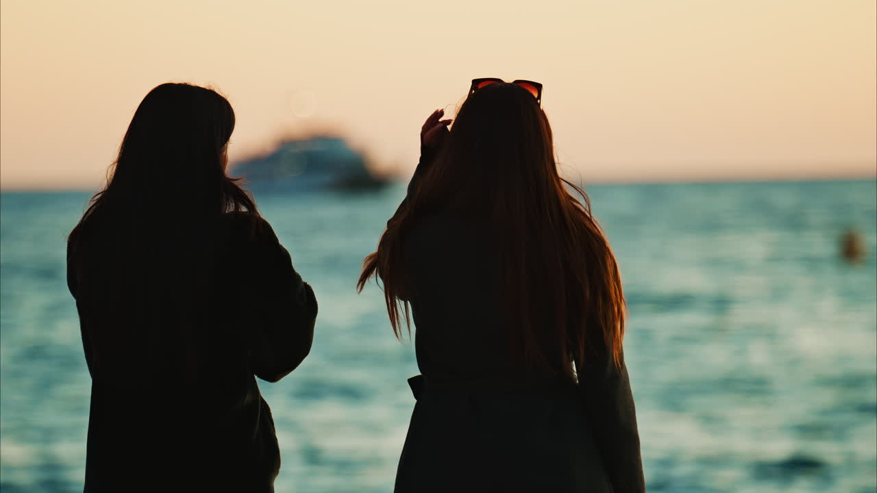 Nice, France - January 10, 2025: Two women talking on the beach and looking at the sea at sunset