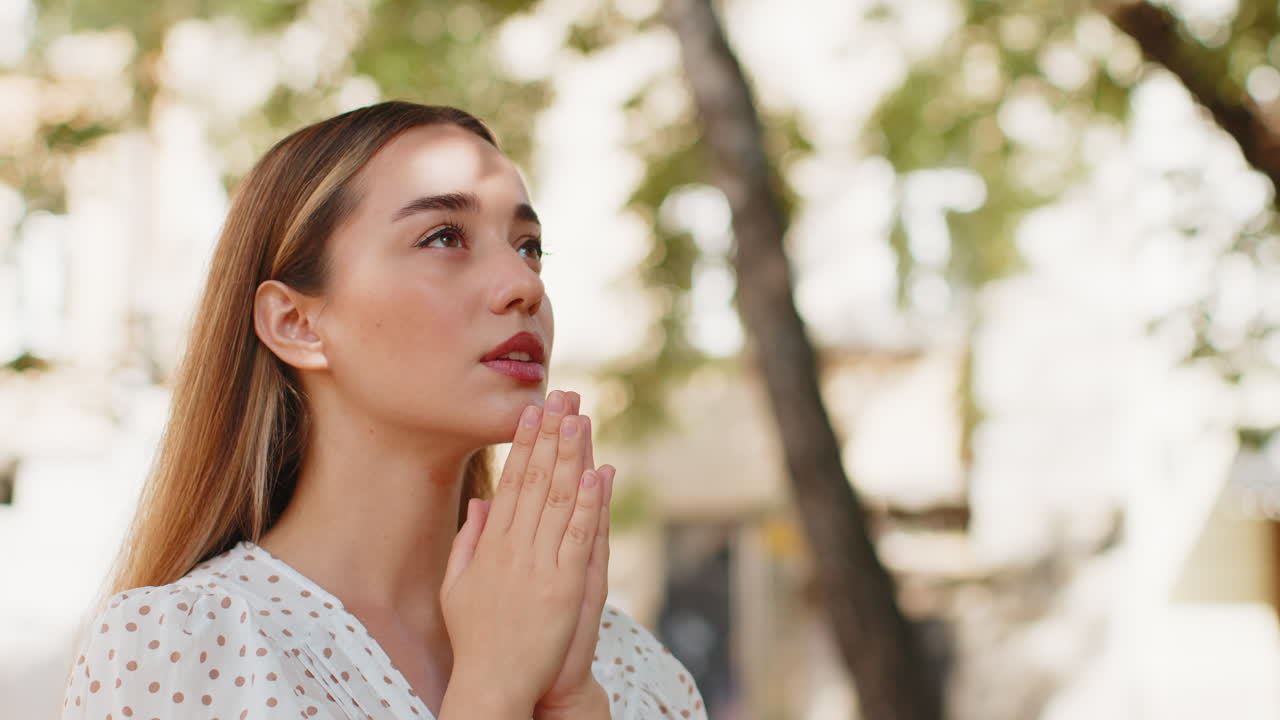 백인 젊은 여성이 눈을 감고 하나님께 기도하며 밖에서 축복, 도움, 용서를 구합니다.