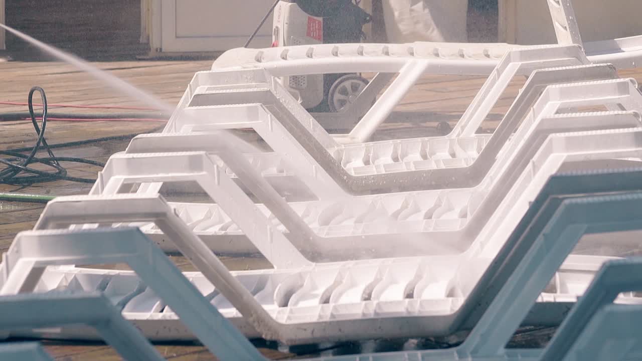 Beach worker washes the beach loungers with a jet of water 2