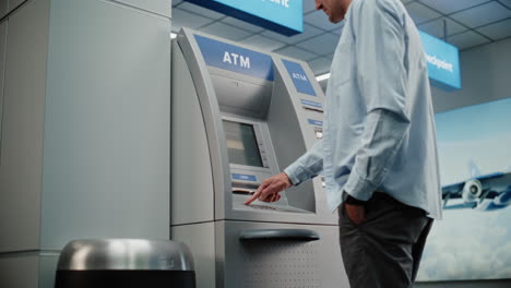 man using atm at airport
