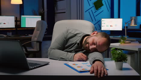 exhausted overworked businessman sleeping on desk table in startup business office