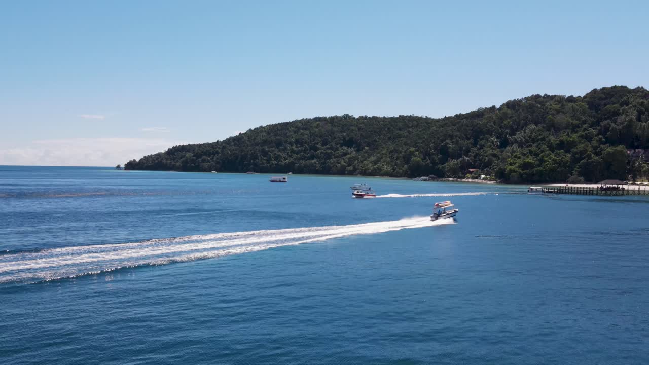 aerial volando sobre botes de velocidad navegando más allá de ir y venir de la isla de manukan