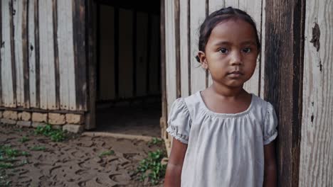 young girl standing near wooden building