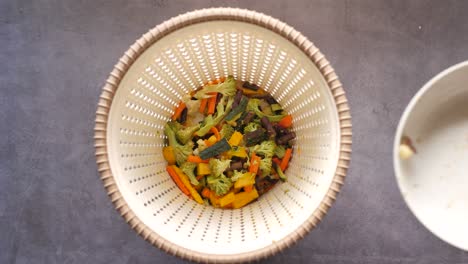 tirando verduras en un cubo de basura