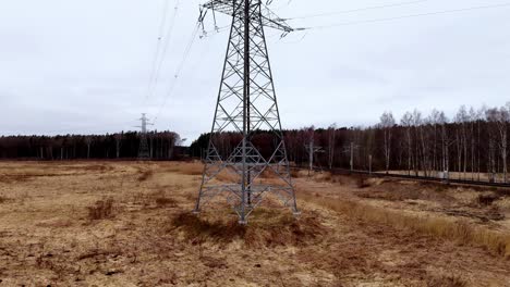 una alta torre de energía está en el medio de un campo
