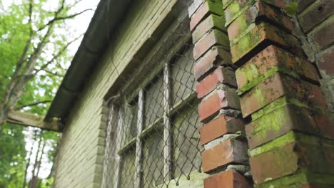 old brick building with moss and rusty window