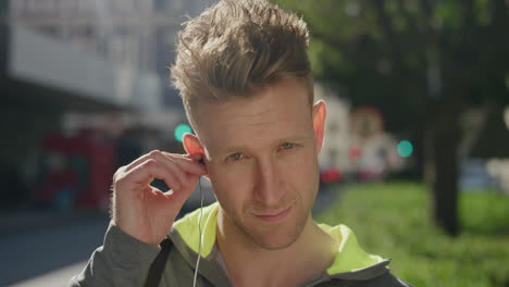 portrait-of-confident-young-man-puts-on-earphones-listening-to-music-enjoying-healthy-urban-lifestyle-travel-in-city-street-background-slow-motion