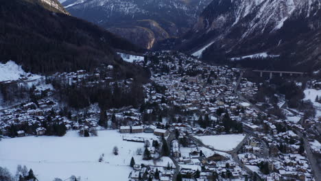 Aerial-tilt-up-from-snow-covered-town-in-valley-to-beautiful-mountain-top