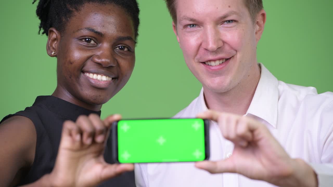Dois jovens profissionais de negócios multiétnicos mostrando um telefone juntos