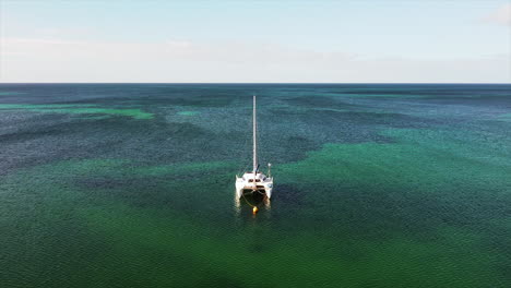 Aerial-view-of-anchored-sailboat-in-the-crystal-clear-waters-of-the-ocean