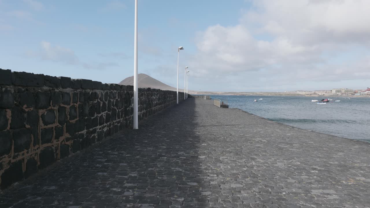 POV view of a rocky path next to the ocean on a sunny day in El Médano, Tenerife, Canary Islands, Spain.