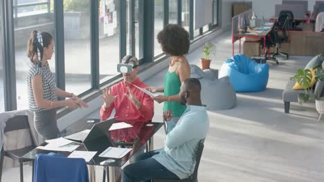 caucasian businessman wearing vr headset while colleagues watching him at office