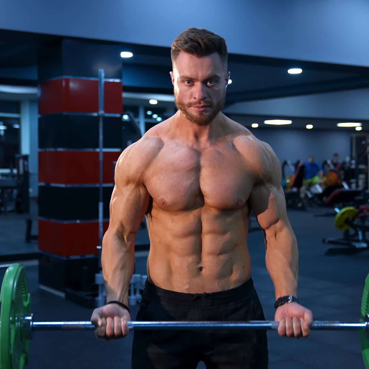 Male athlete with strong body and naked torso lifts barbell in modern gym. Slow motion